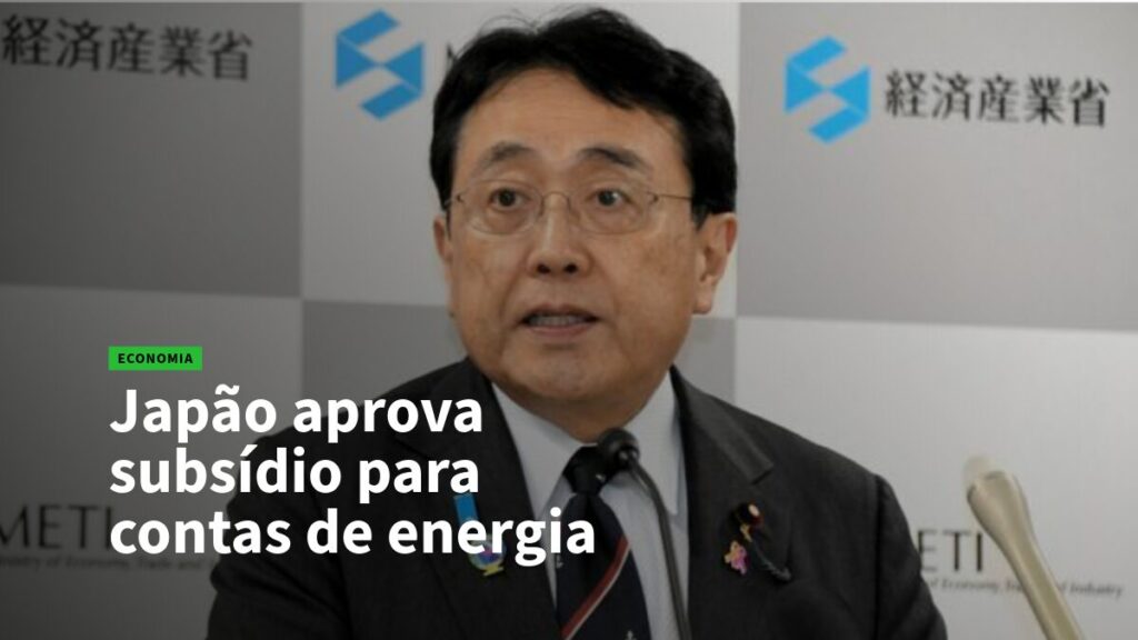 Executivo japonês em coletiva de imprensa, logotipos do ministério ao fundo; notícia sobre subsídio de energia no Japão.