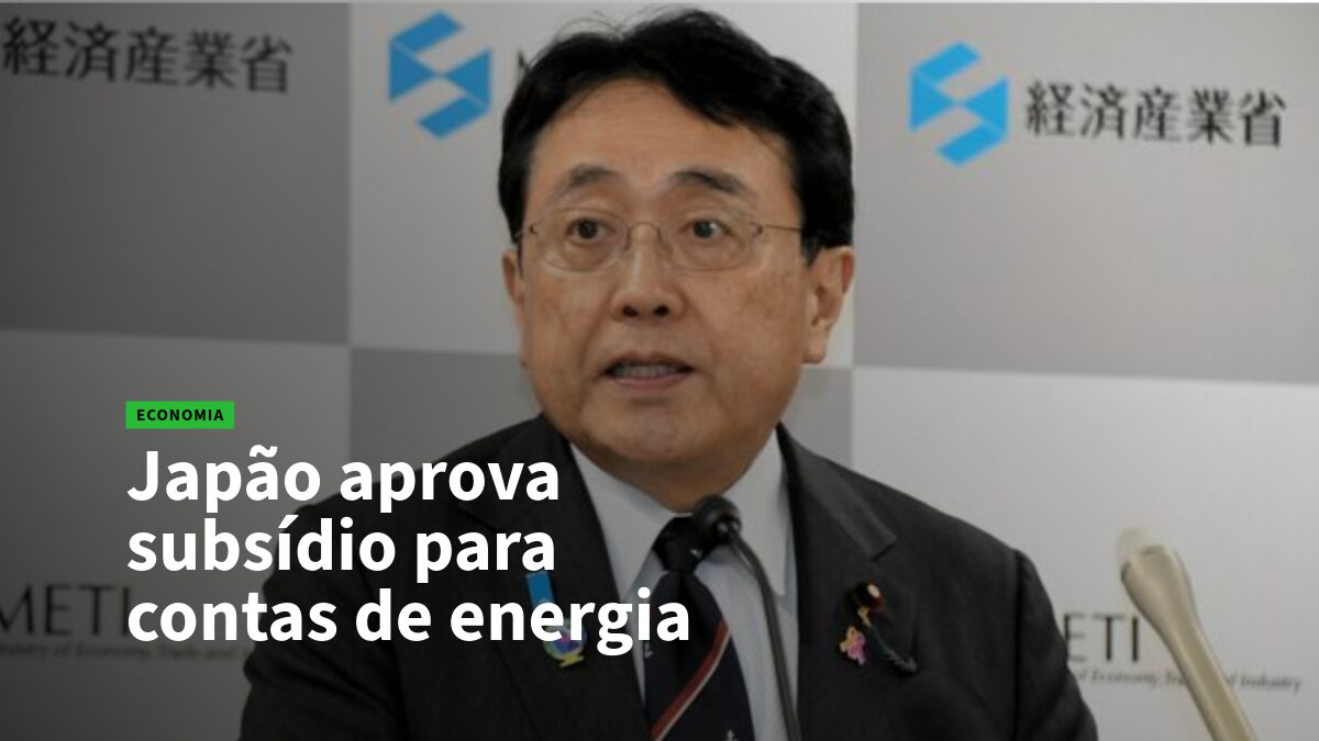 Executivo japonês em coletiva de imprensa, logotipos do ministério ao fundo; notícia sobre subsídio de energia no Japão.