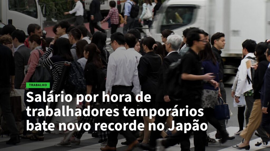 Crowded city crosswalk with businesspeople walking; headline reports Japan's temporary workers' hourly wage hits a new record.