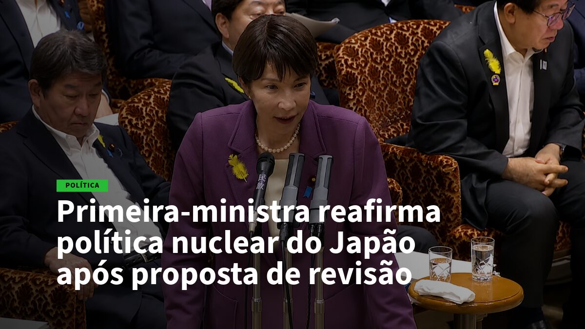 Primeira-ministra japonesa em blazer roxo fala aos jornalistas, com vários microfones à sua frente.