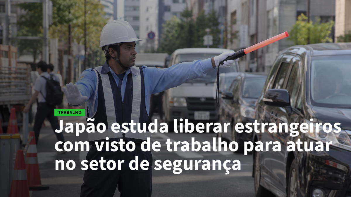 Homem com capacete branco, colete refletivo e luvas aponta com bastão laranja para controlar o trânsito em uma rua movimentada.